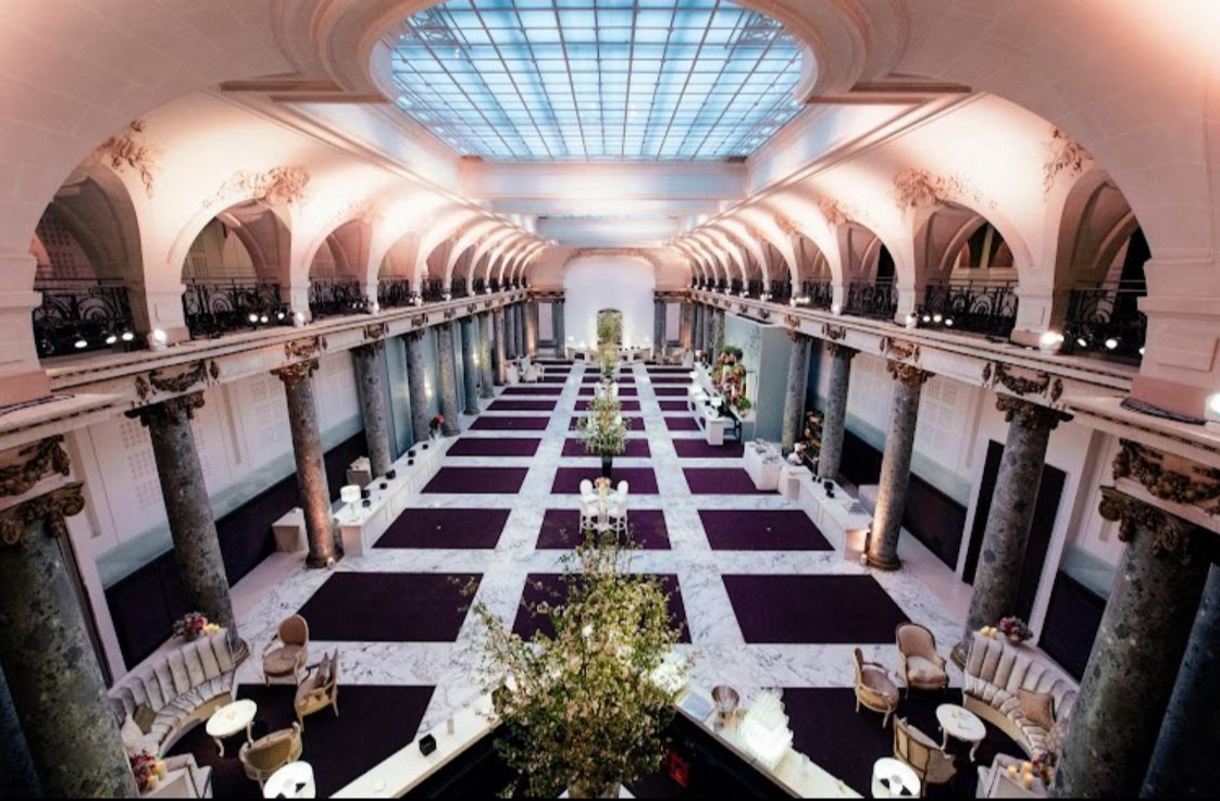 Vue d’ensemble d’une salle avec colonnes, galeries et verrière avant l’installation du défilé