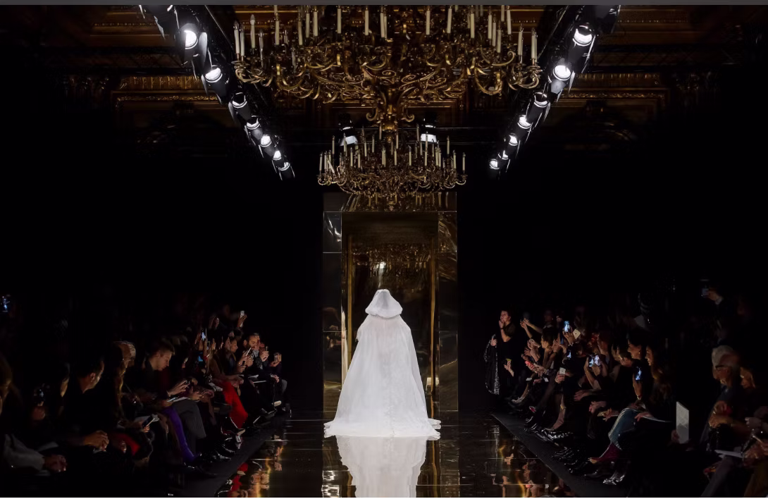 Silhouette de mariée blanche sur un podium réfléchissant sous des lustres